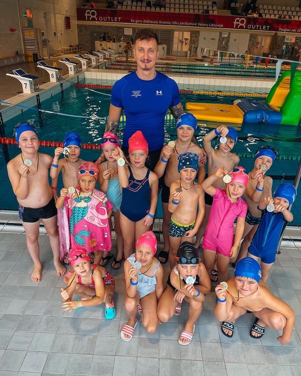 Treneris Aleksandras su vaikais, rodančiais plaukimo medalius